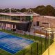 A dusk view of the tennis courts at Glen Waverly Sports Hub with the primary building lit up